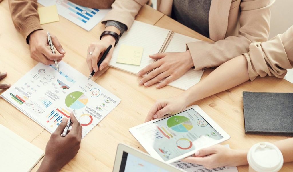 A diverse team of professionals collaborating over charts and graphs during a business meeting.